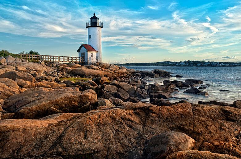 A lighthouse on some rocks by the ocean