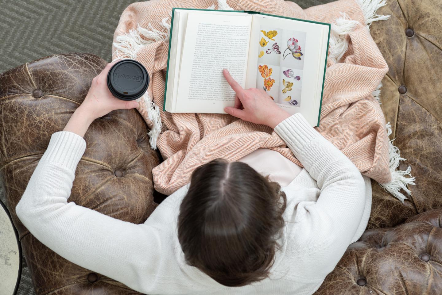 Top down image of a person reading a book on a couch