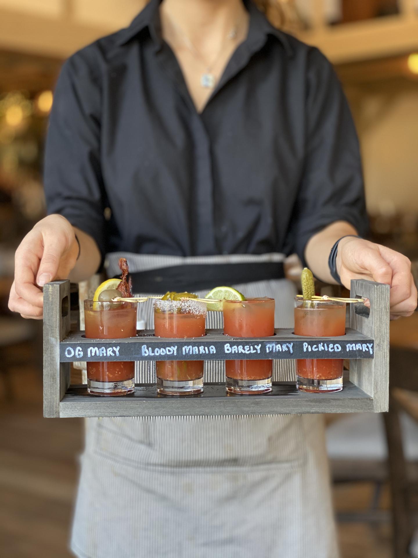A waiter holding a flight of bloody mary's