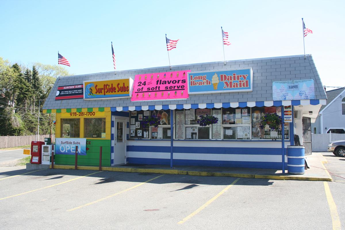 Retro diner with colorful signage, flags on the roof, and flower baskets.