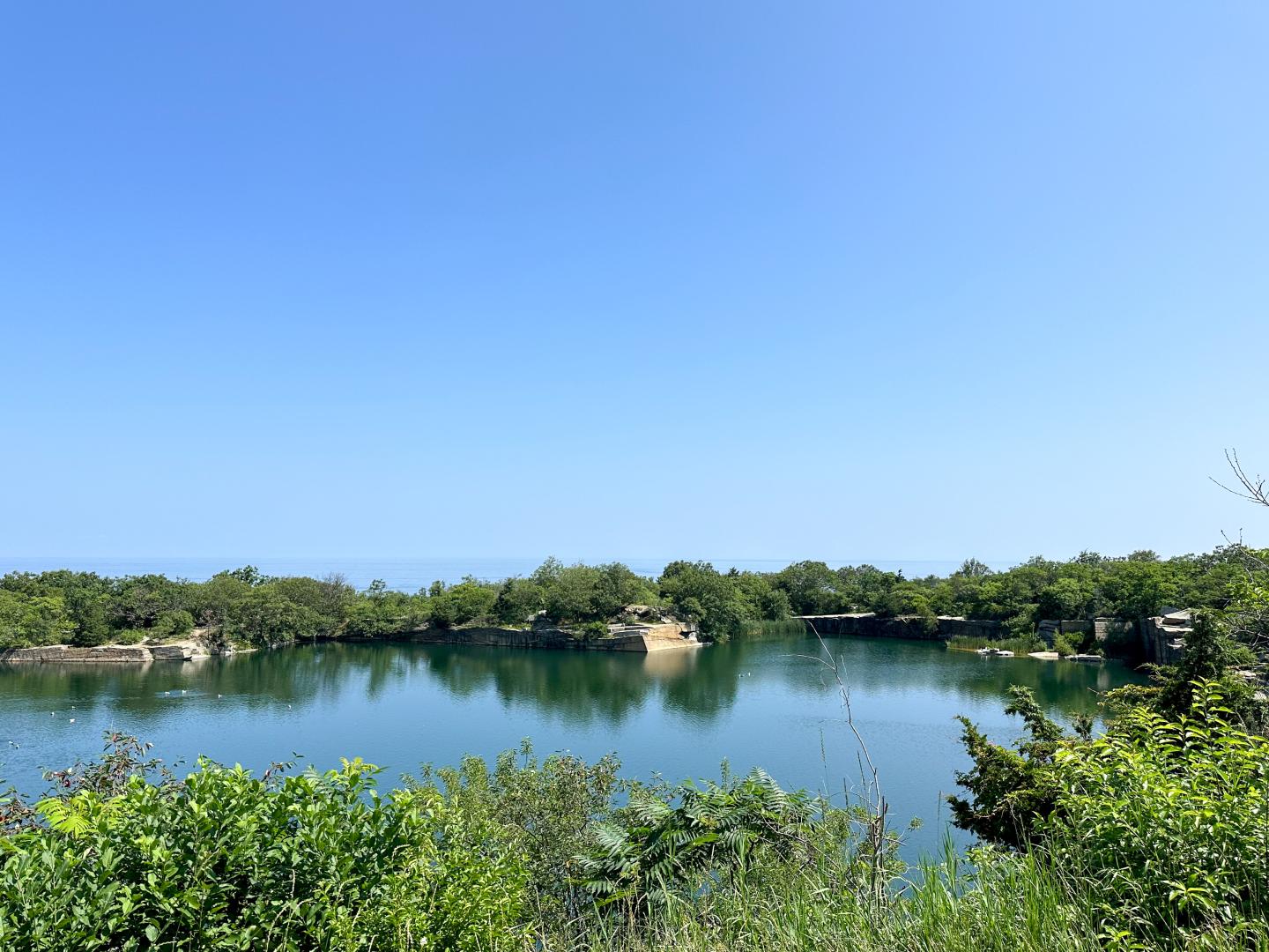 Blue lake surrounded by lush greenery under a clear sky.
