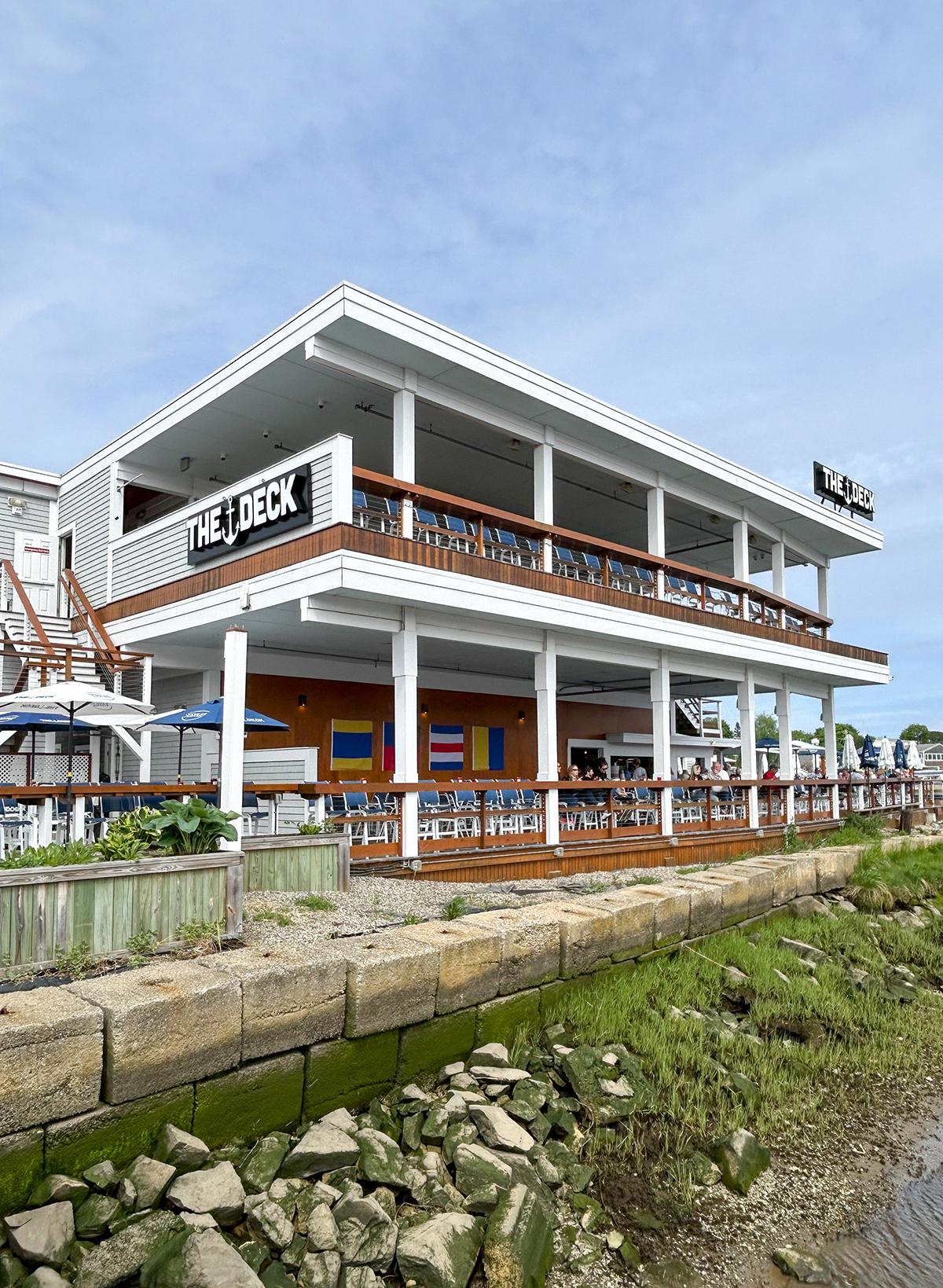 Two-story restaurant with wooden railings and bright signs, under a blue sky.
