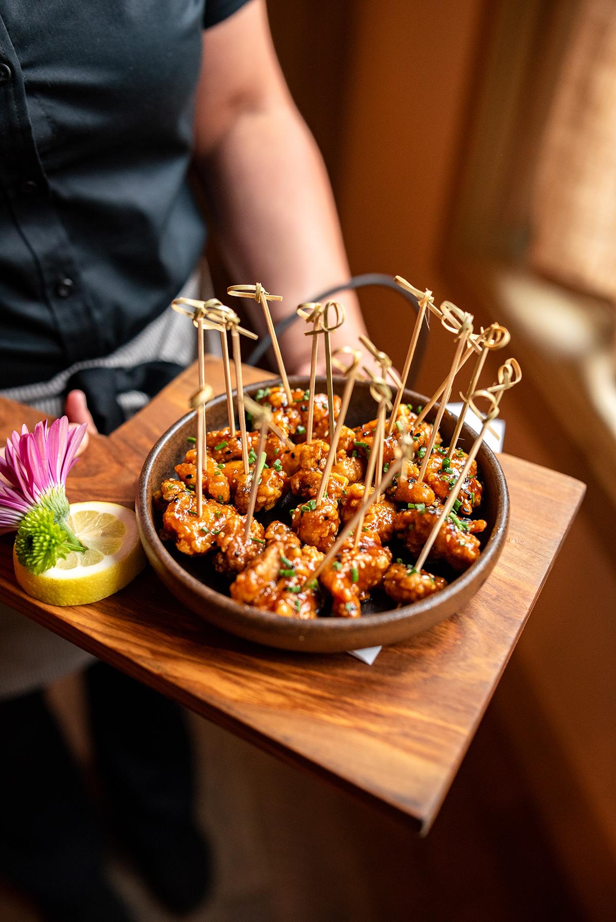 Savory appetizers on skewers served on a wooden tray.