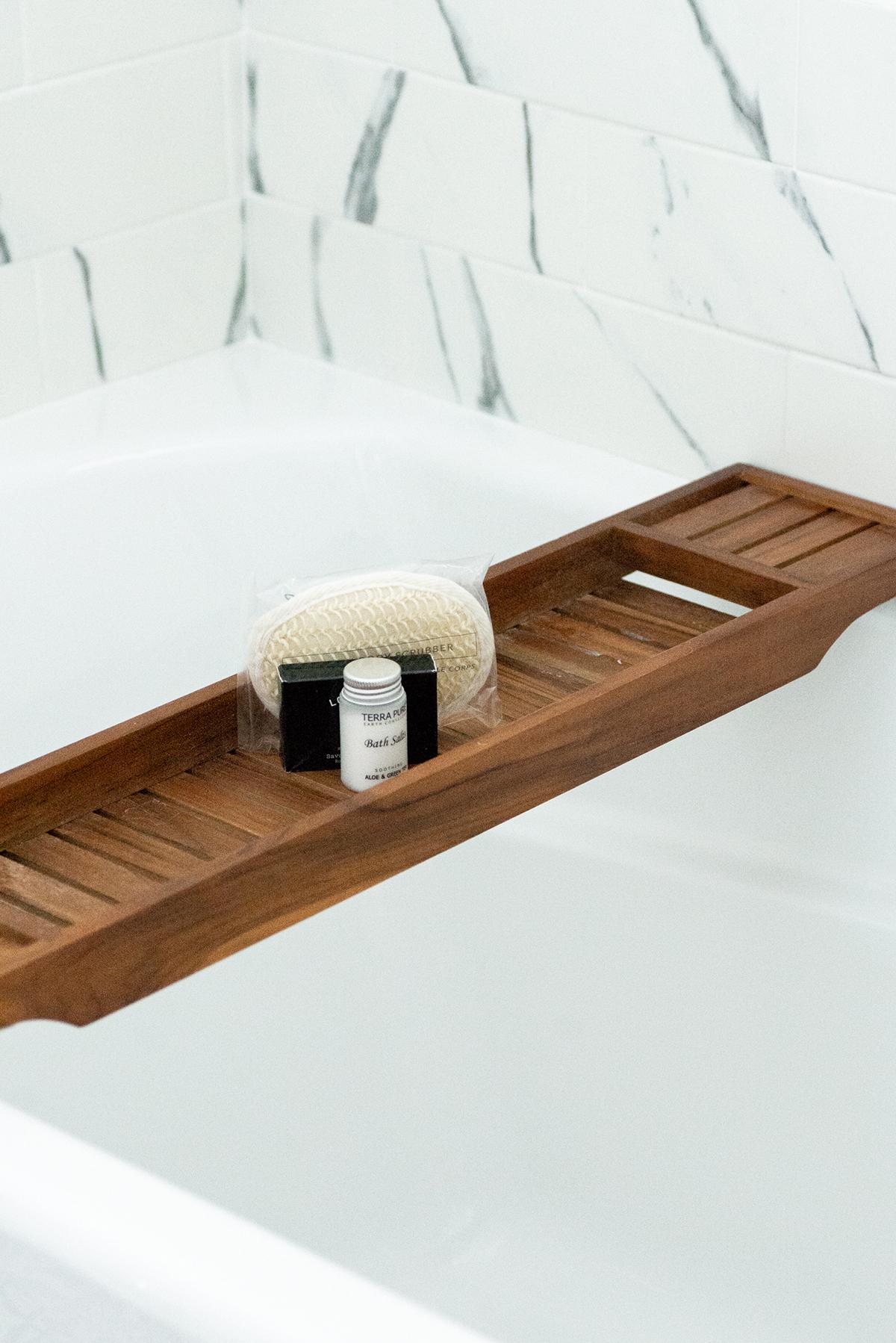 Wooden bathtub tray with soap, sponge, and bottle.