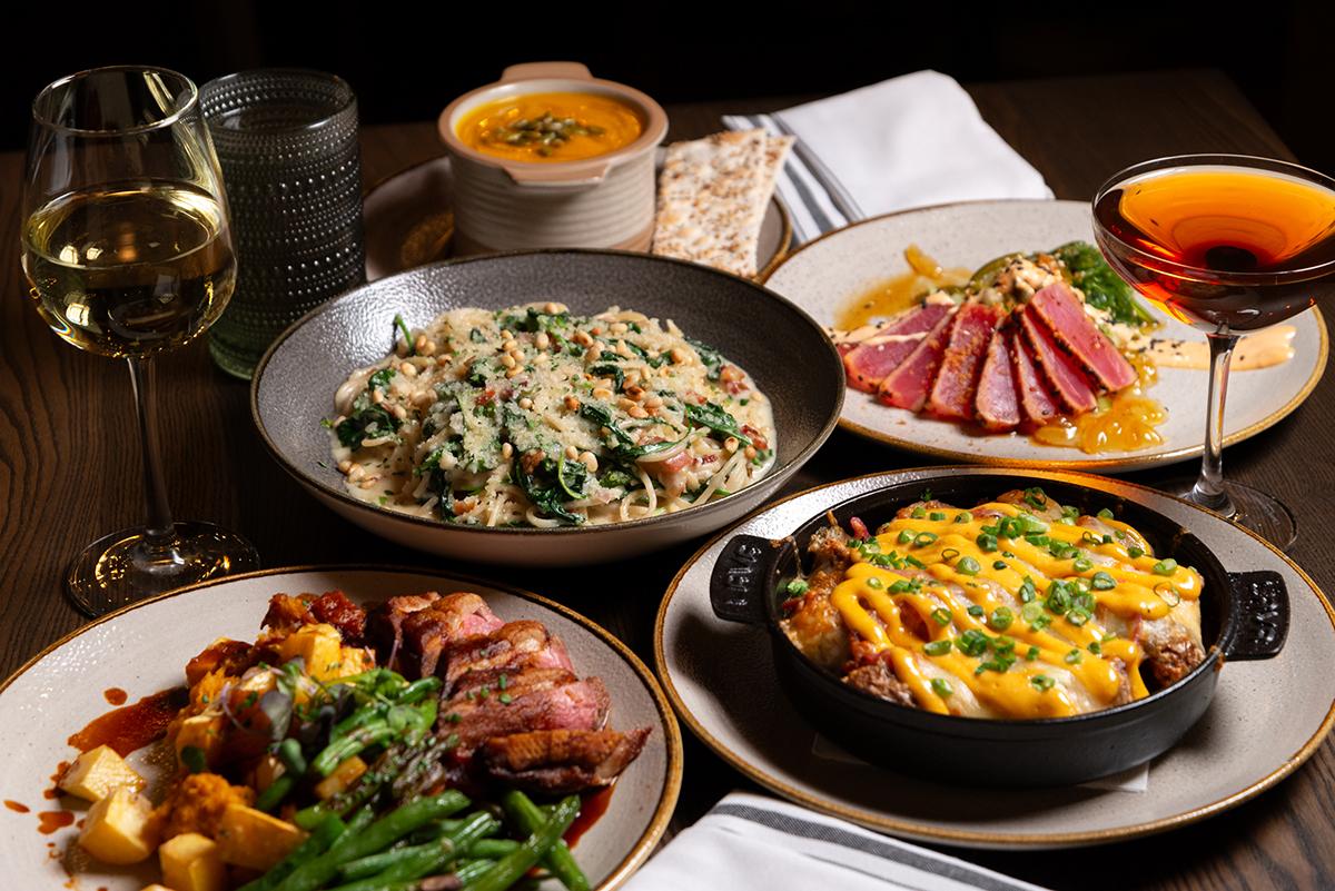 A table with various gourmet dishes and two glasses of drinks.