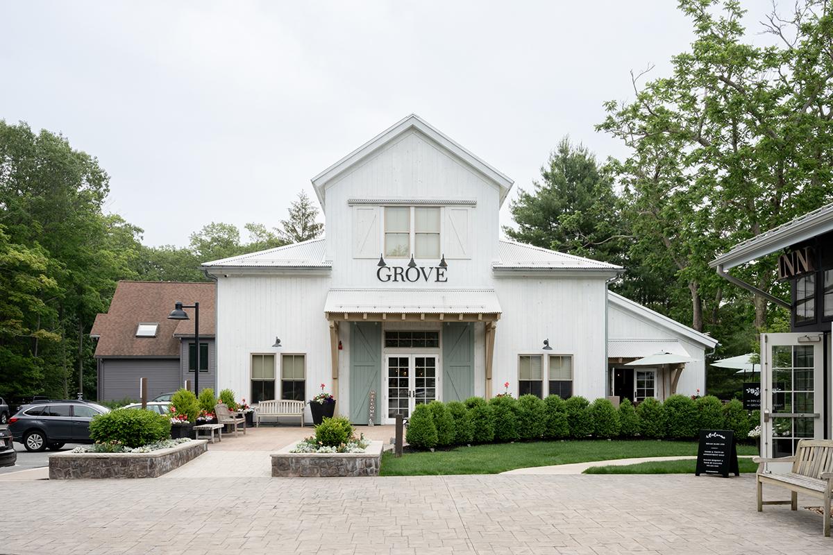 White building with a sign, surrounded by greenery and parked cars.