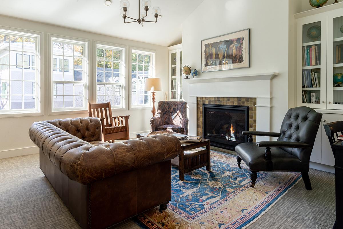 Cozy living room with sofas, armchairs, fireplace, and large windows.