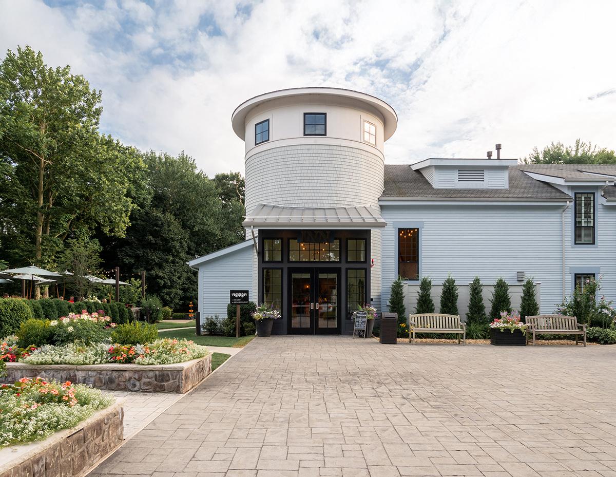 White building with a round tower, surrounded by gardens and benches.