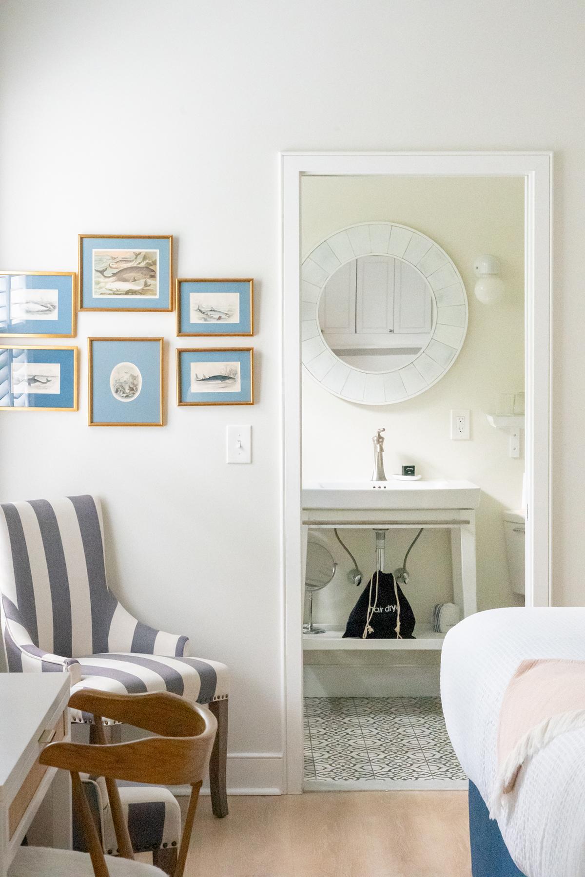 Cozy bedroom with striped chair, wall art, and bathroom view.