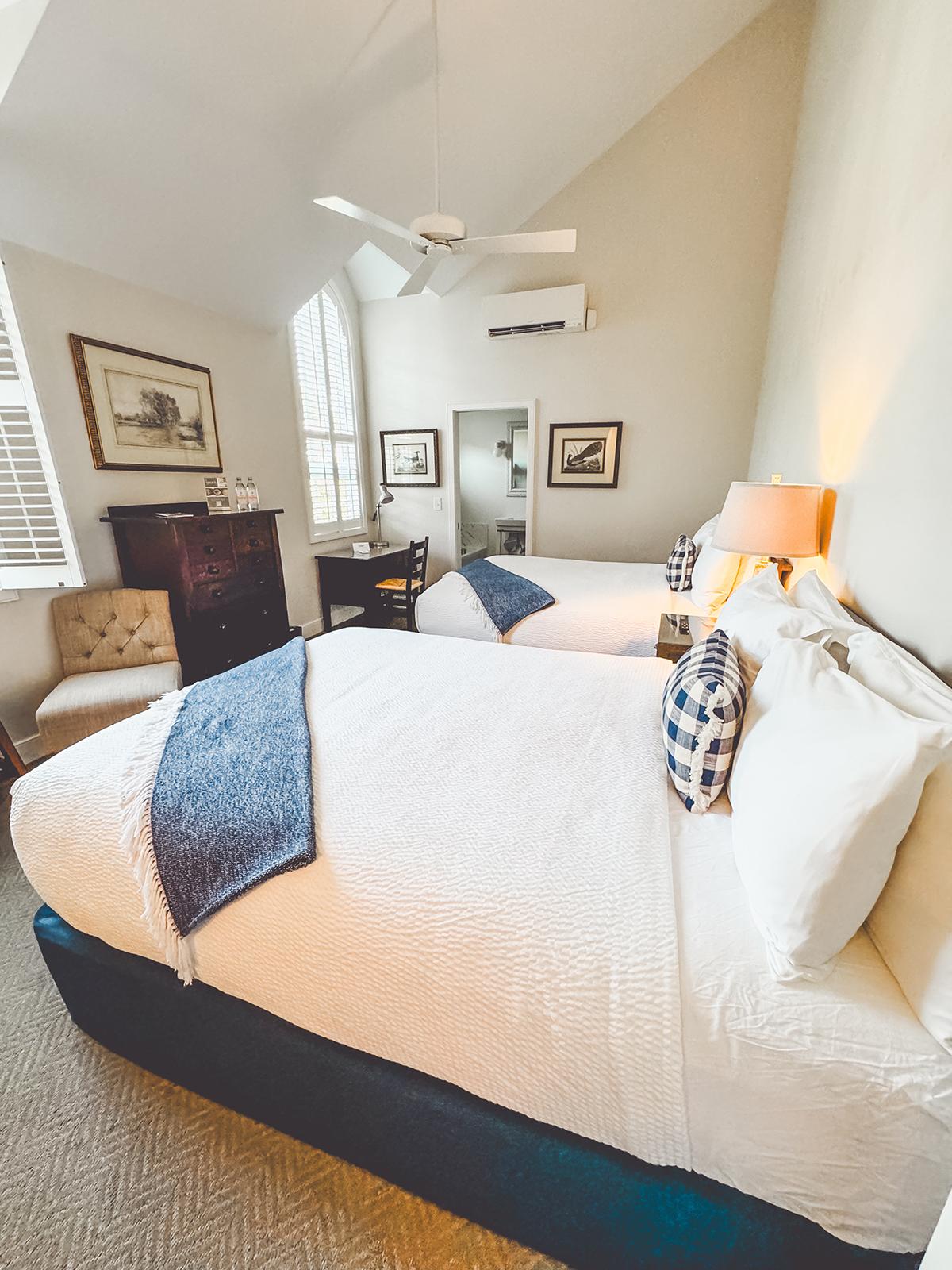 Cozy bedroom with two beds, blue accents, and warm lighting.
