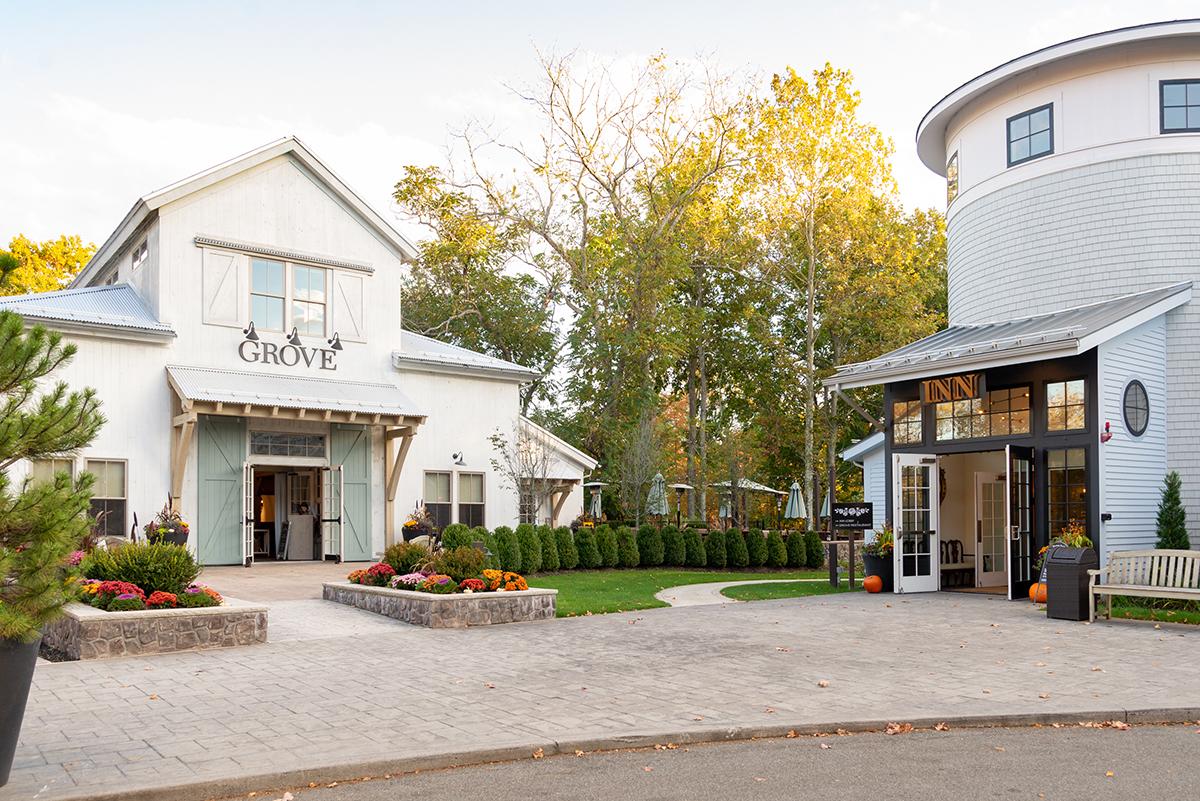 Rustic buildings with autumn trees and paved walkway, sunny day.