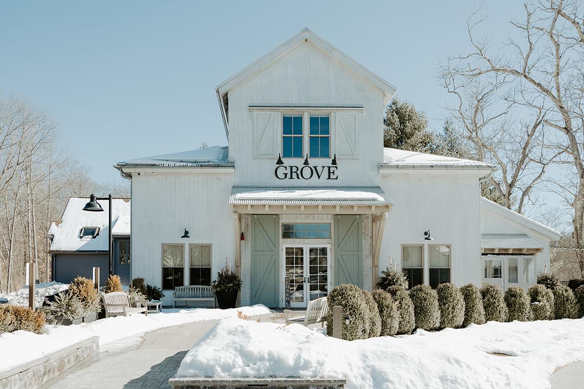 Rustic white building with snow-covered path and bare trees.