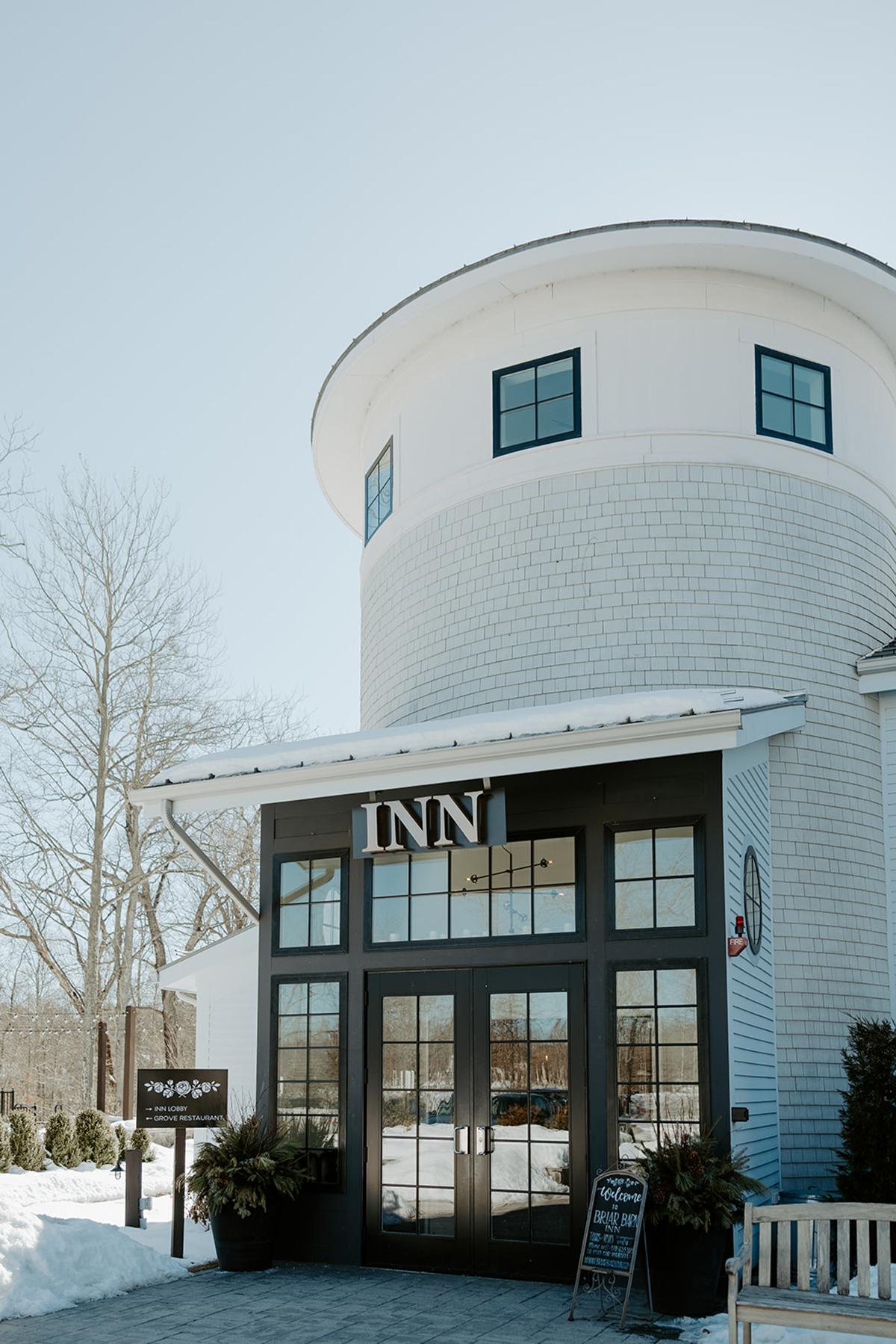 White cylindrical inn with black framed windows, snowy setting.