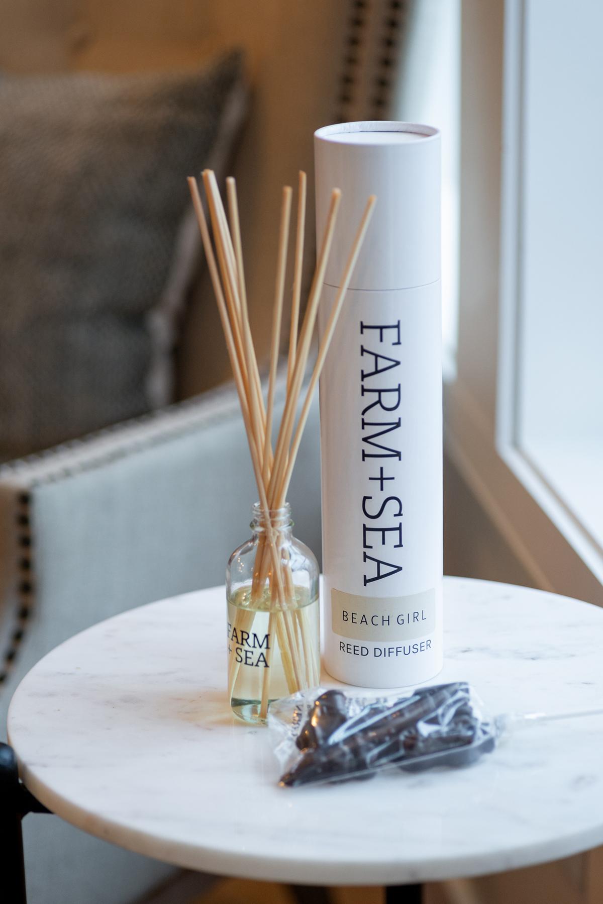 Diffuser sticks and a tall Farm+Sea container on a round table.