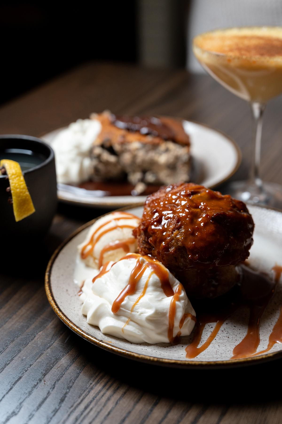 Caramel dessert with whipped cream, coffee, and cocktail on a wooden table.