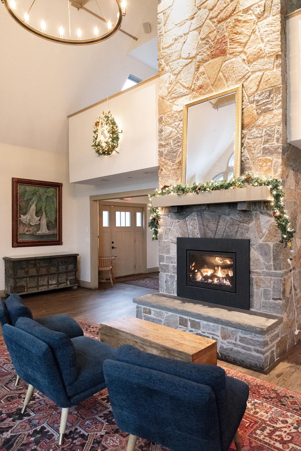 Cozy living room with stone fireplace, blue chairs, and holiday wreath.