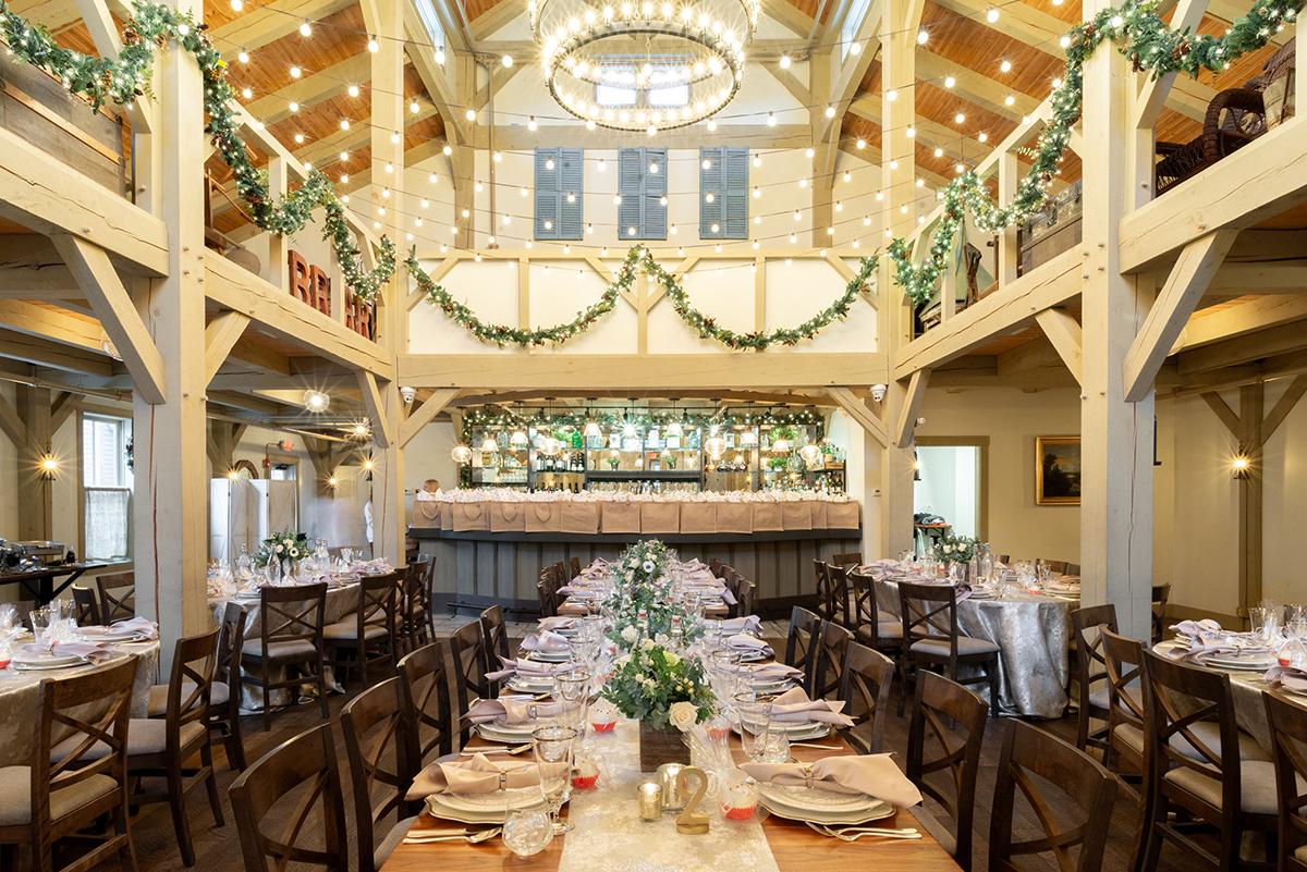Elegant dining hall with long tables, festive garlands, and ceiling lights.