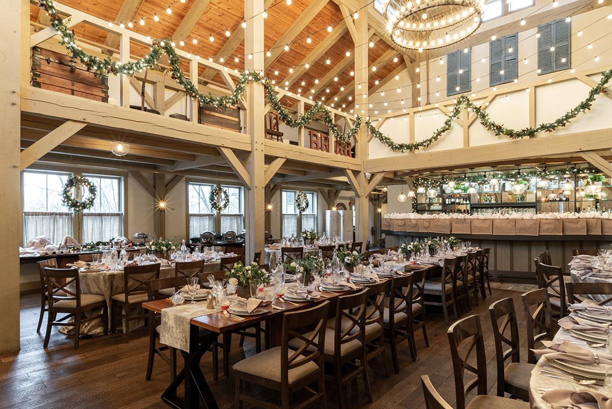 Rustic banquet hall with wooden tables, garlands, and string lights.