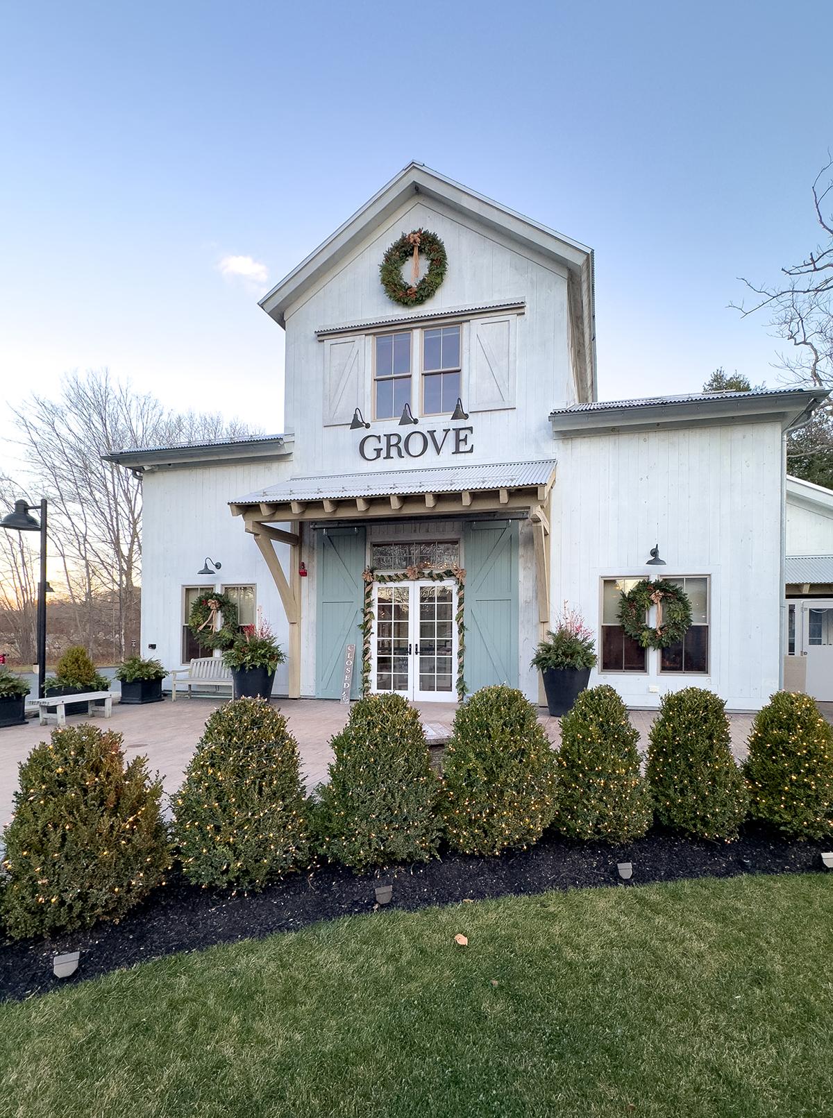 Boutique store with wreaths and shrub landscaping under a clear sky.