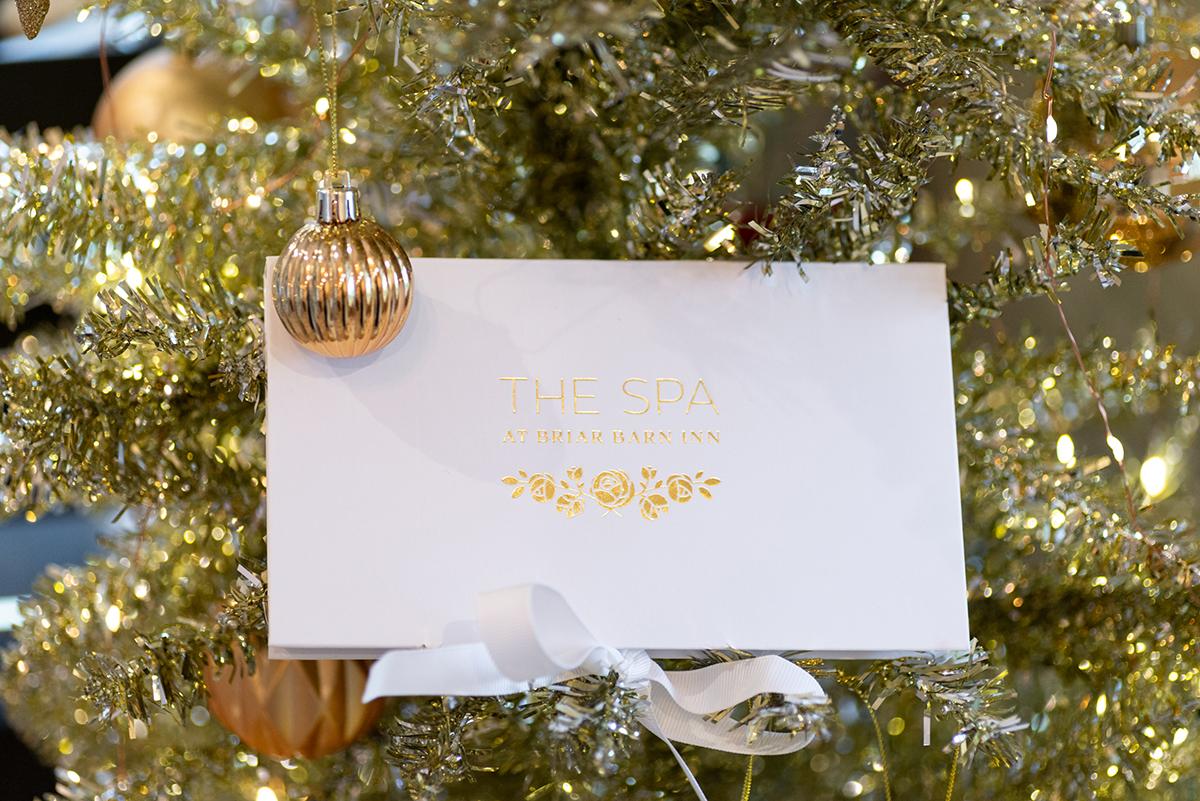 A white spa gift card on a decorated Christmas tree.