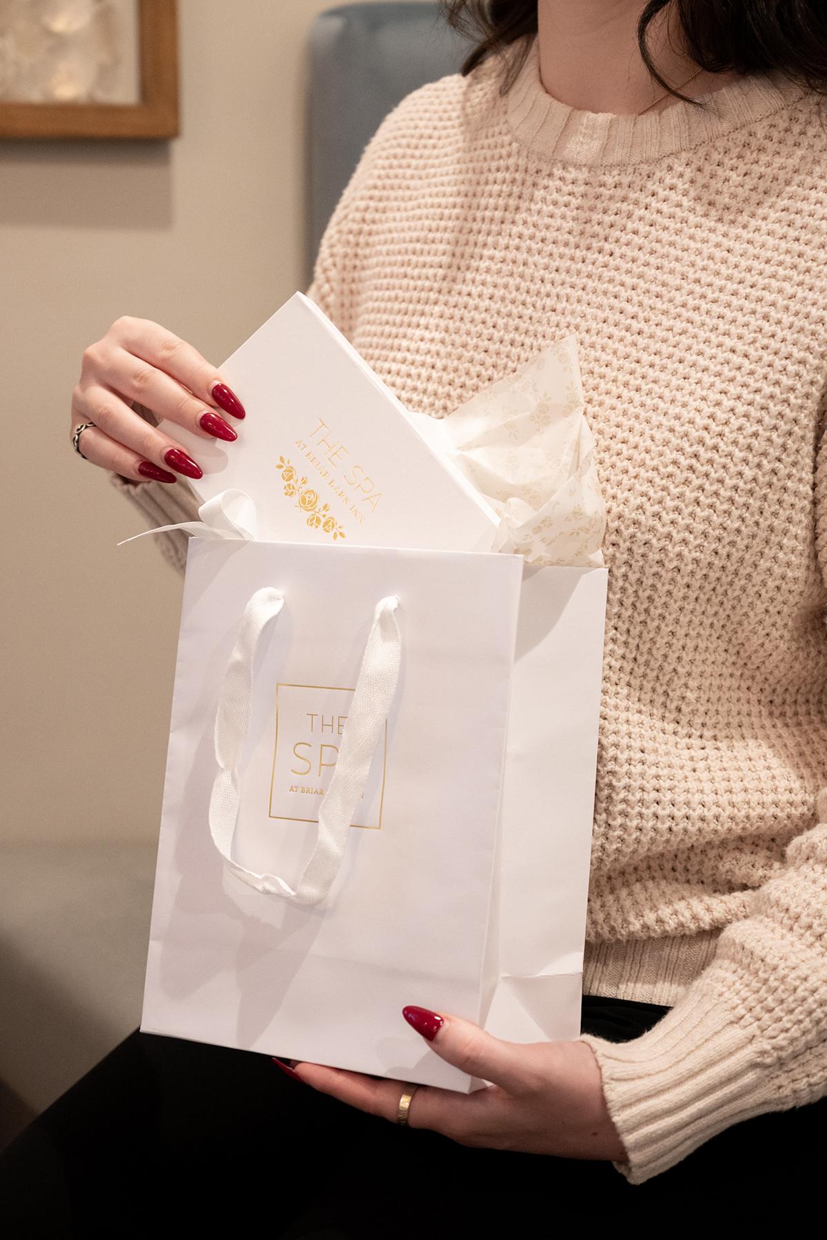 Woman holding a white gift bag with a card inside.