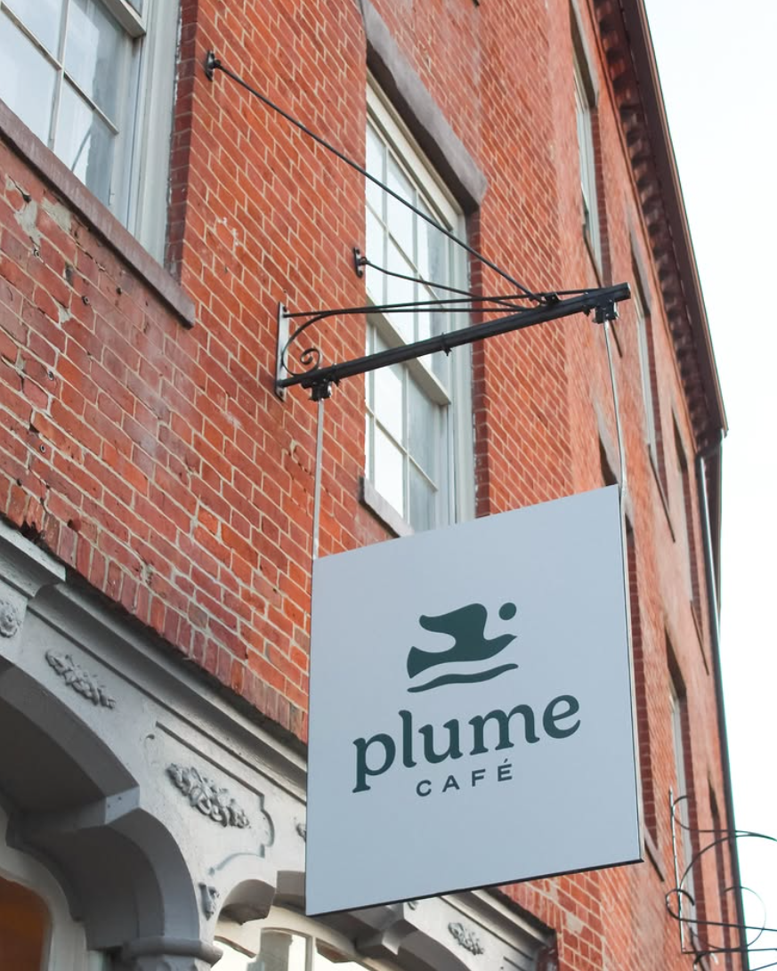 Plume café sign on a red brick building.