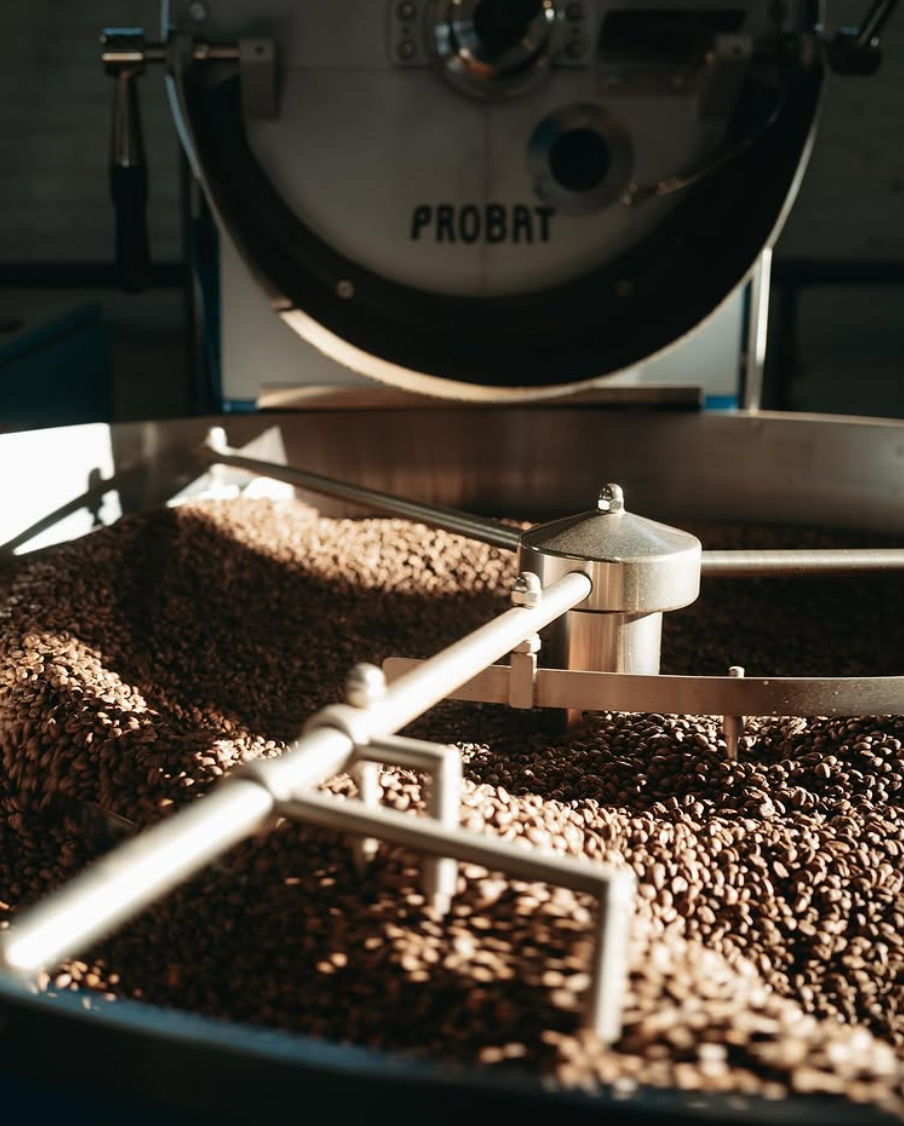 Coffee beans in a roasting machine, sunlight highlights texture.