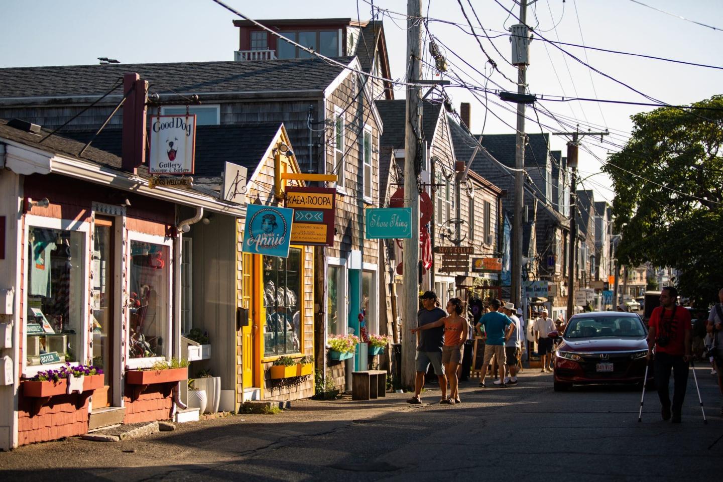 Narrow street lined with colorful shops and people walking.