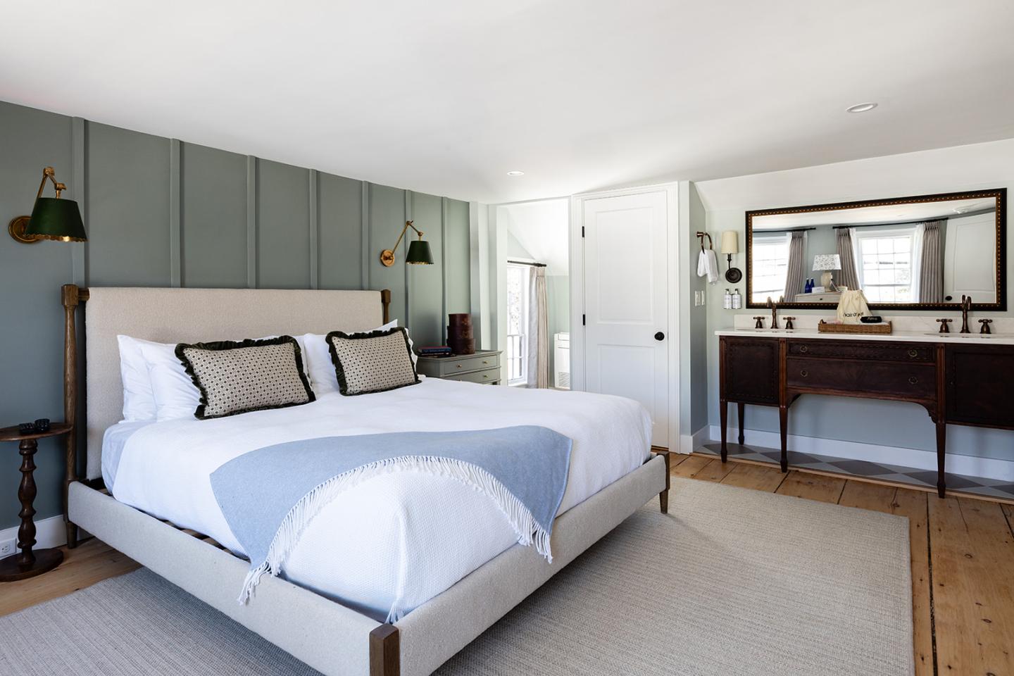 Cozy bedroom with a large bed, green accent wall, and wooden furniture.