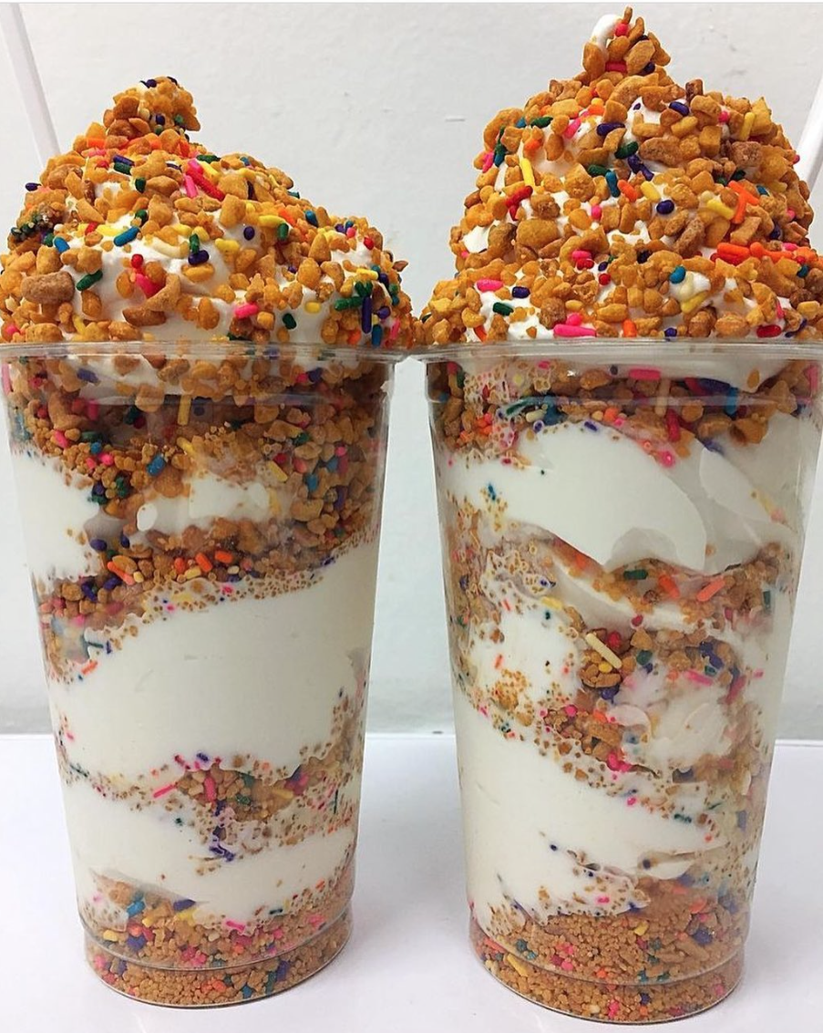 Two cups of soft serve ice cream with cereal and rainbow sprinkles.