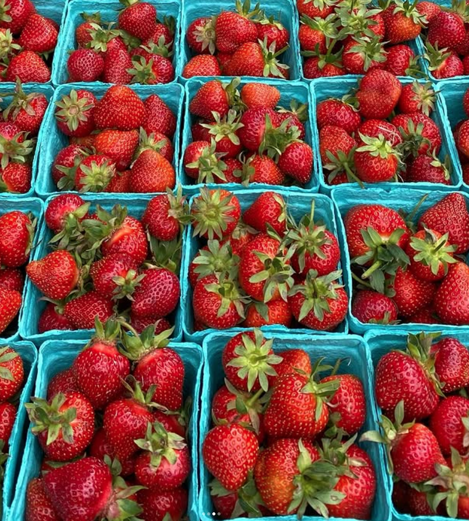 Fresh strawberries in turquoise baskets arranged on a table.