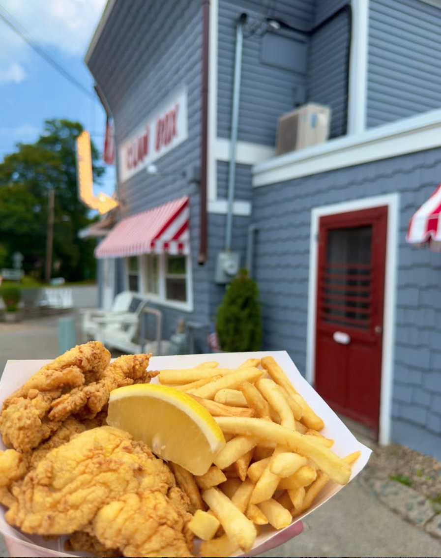Fried seafood and fries in a tray outside a blue building with red doors.