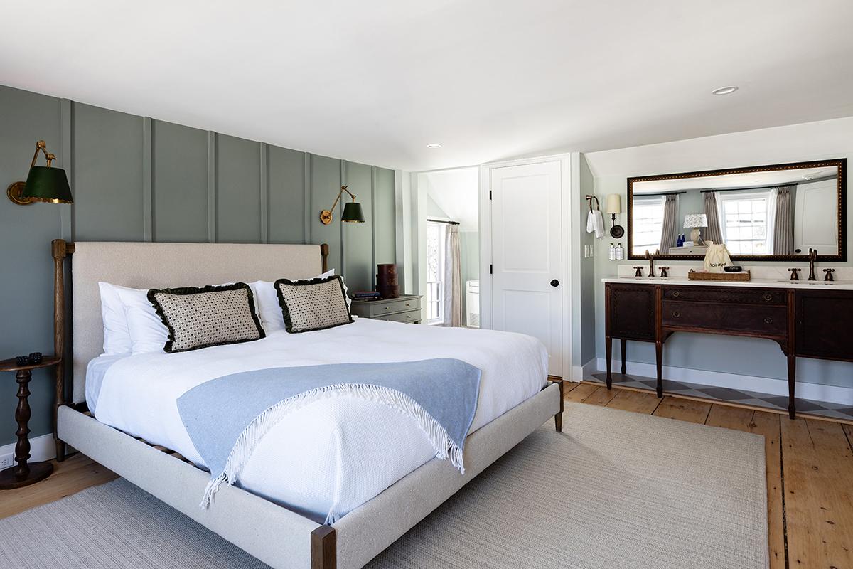 Bright bedroom with a large bed, blue accent wall, and wooden furniture.
