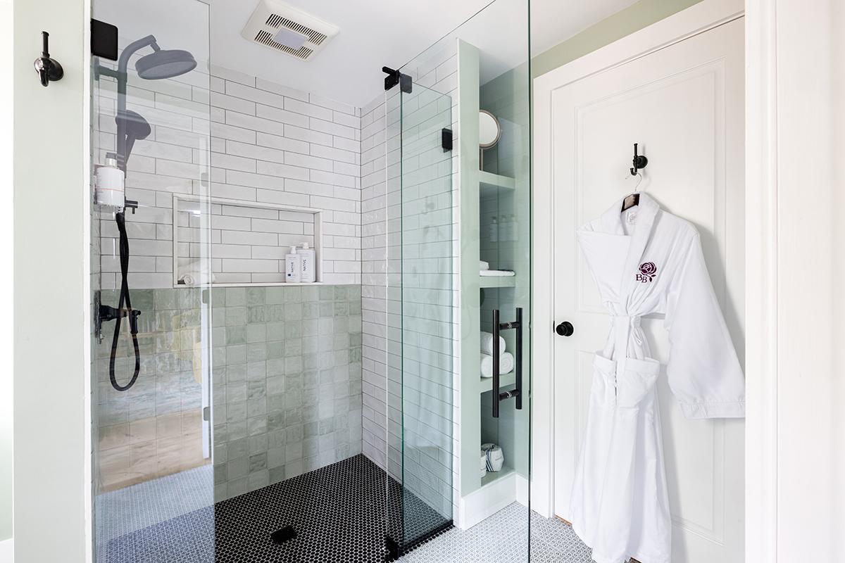 Walk-in shower with robe on door hook.