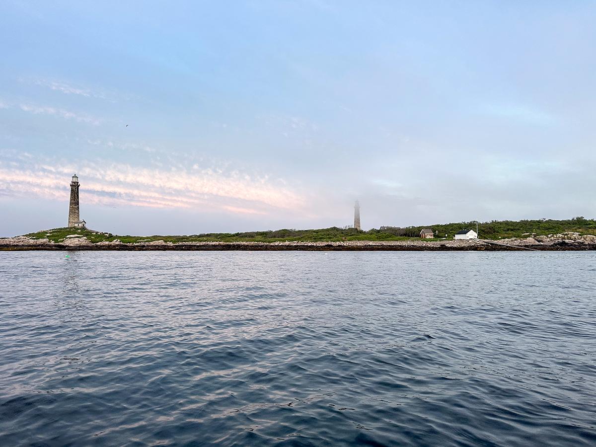 Calm sea with distant lighthouse against blue sky.