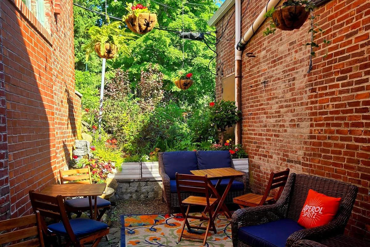 Cozy brick patio with tables, chairs, and potted plants.