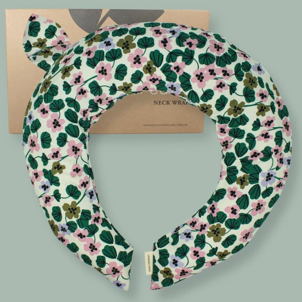 Floral print neck wrap on a cardboard box, green and pink colors.
