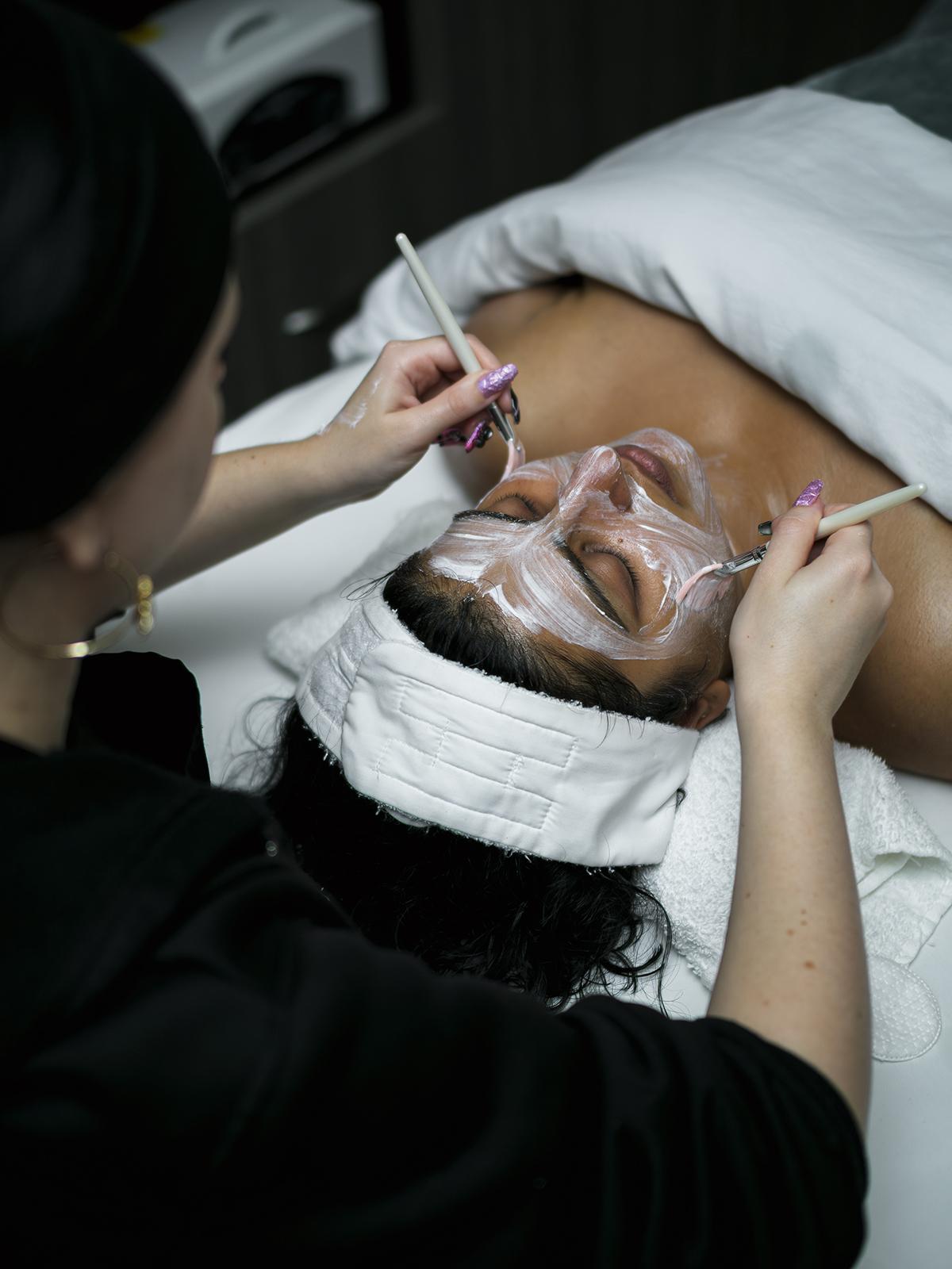 Client receiving a facial treatment with a mask and brushes.