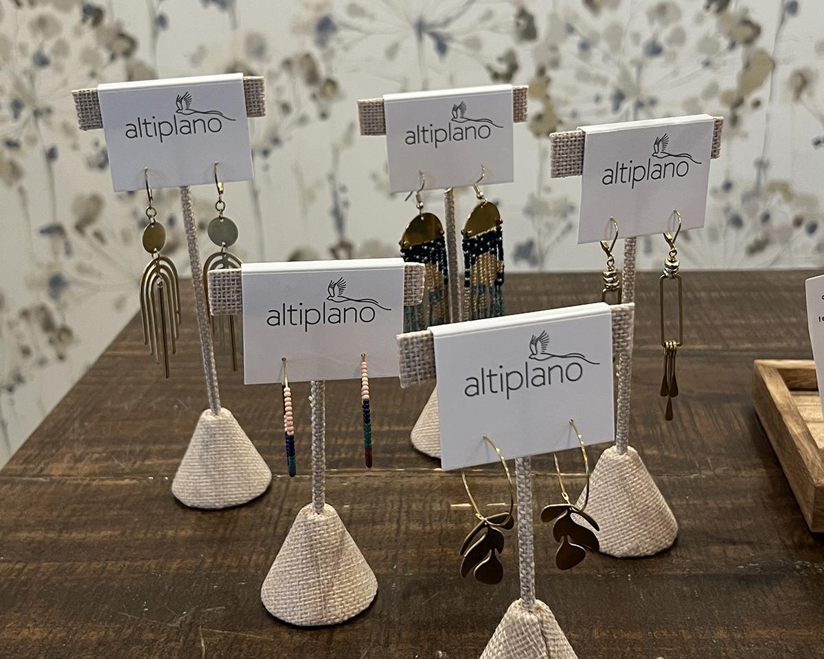 Display of “altepiano” jewelry cards on a wooden table with stone bases.