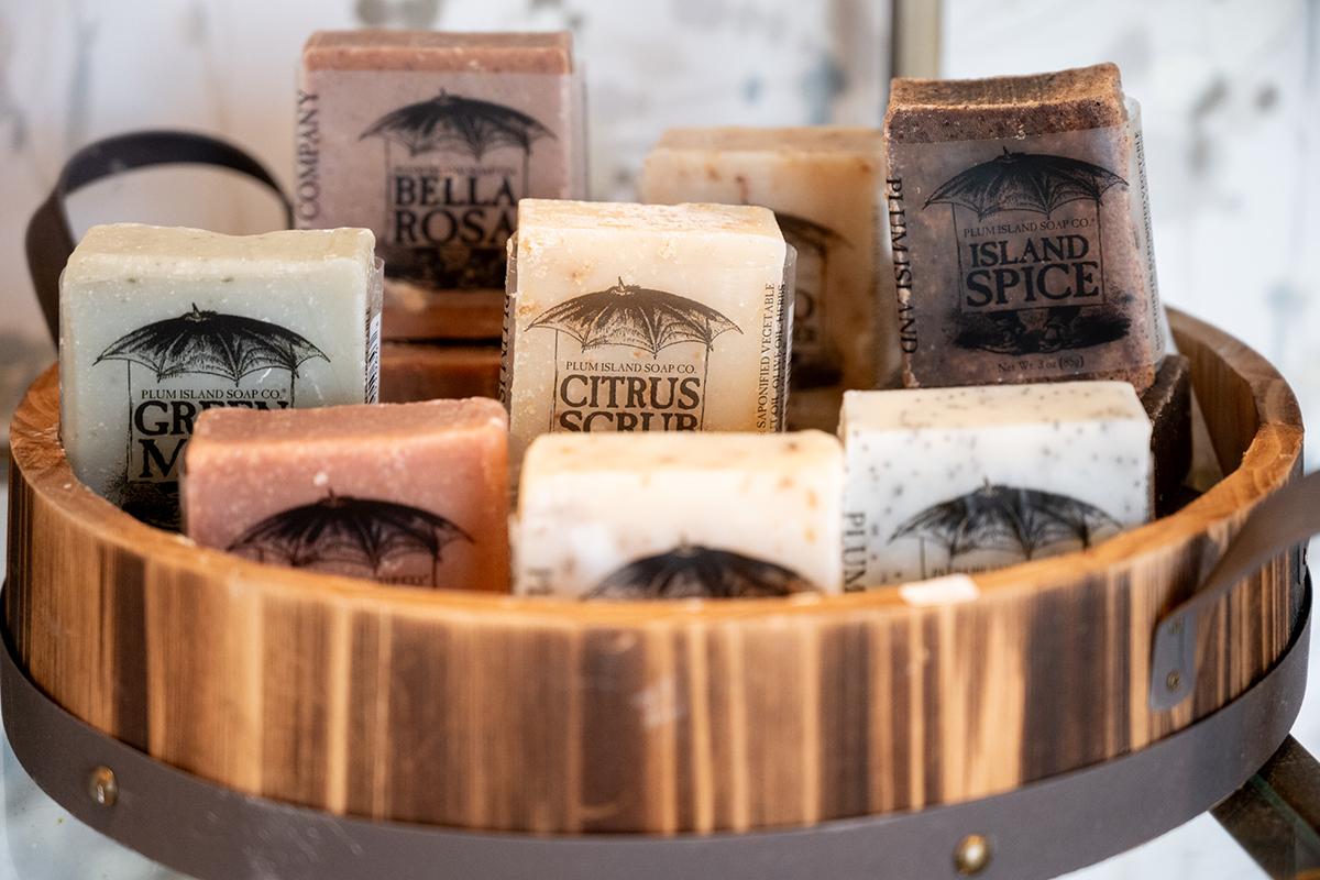 Assorted artisan soap bars displayed in a wooden bowl.